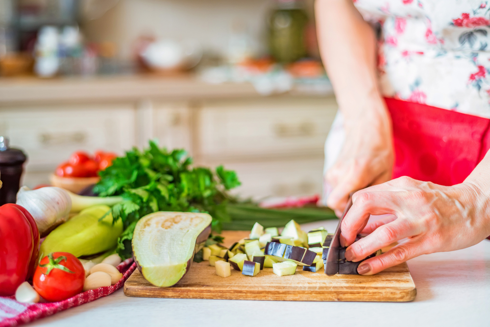 Older Woman slicing eggplant Lndspe